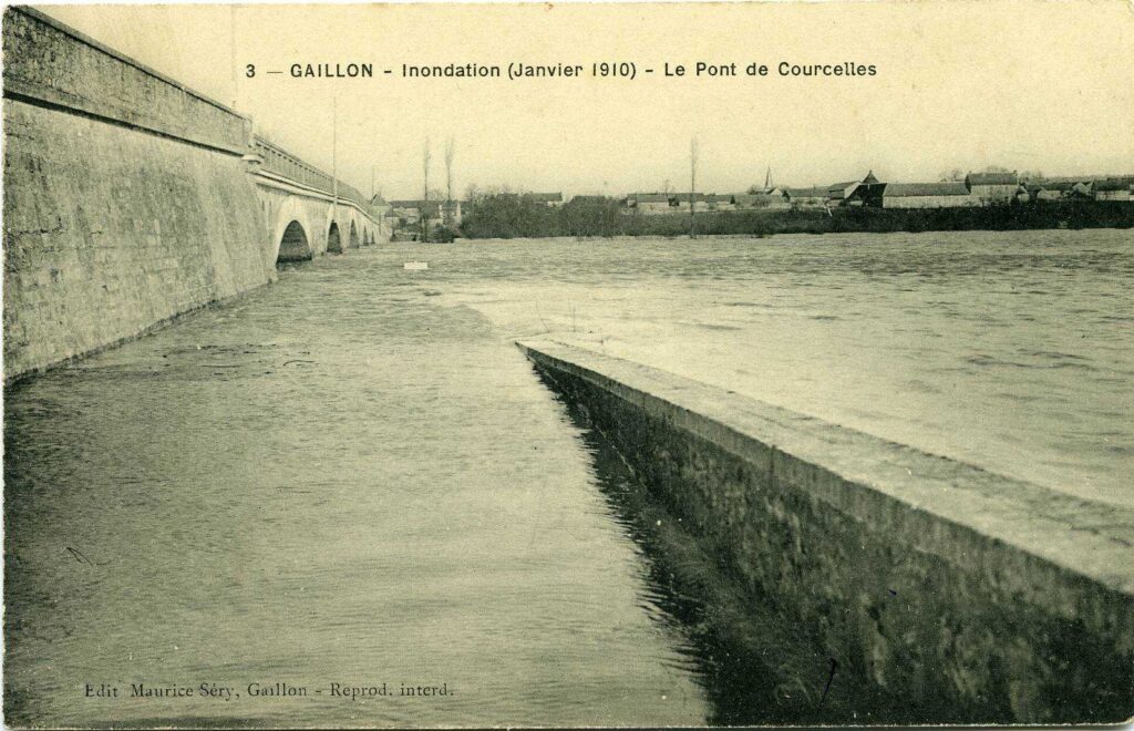 Carte postale 1910. Courcelles sur Seine (27). Source : collection Archives Départementales 27. Vue sur le pont de Courcelles sur Seine avec pour perspective l'église de Courcelles sur Seine