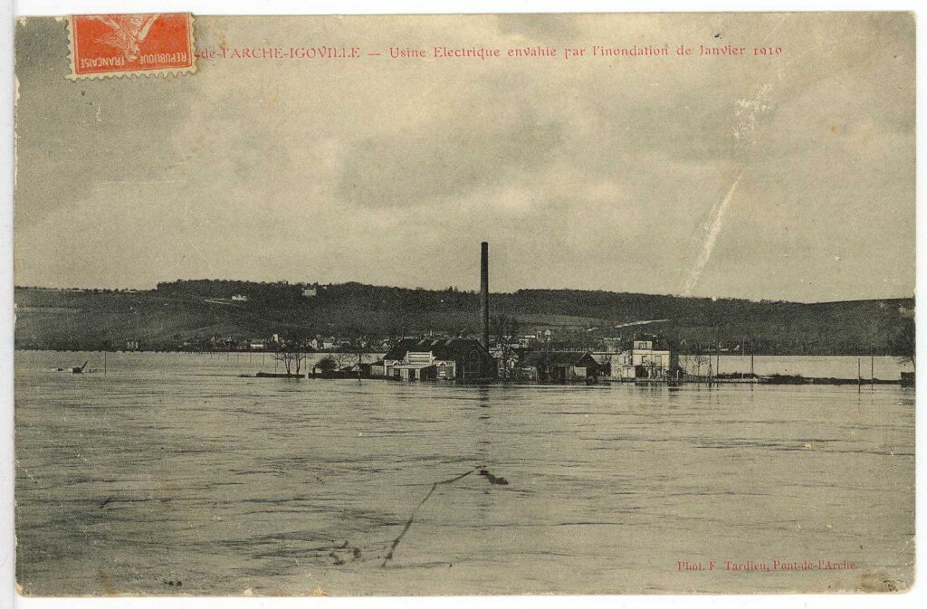 Carte postale 1910. Pont de l'Arche-Igoville : usine électrique envahie par l'inondation de janvier 1910 (source : Archives Départementales 27)