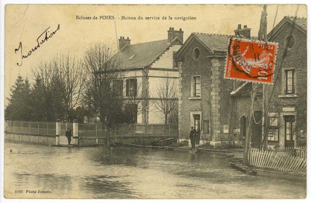 Carte postale 1910. Ecluses de Poses, maison du service de la navigation où l'eau arrive jusque la devanture du bâtiment (source : Archives Départementales 27)